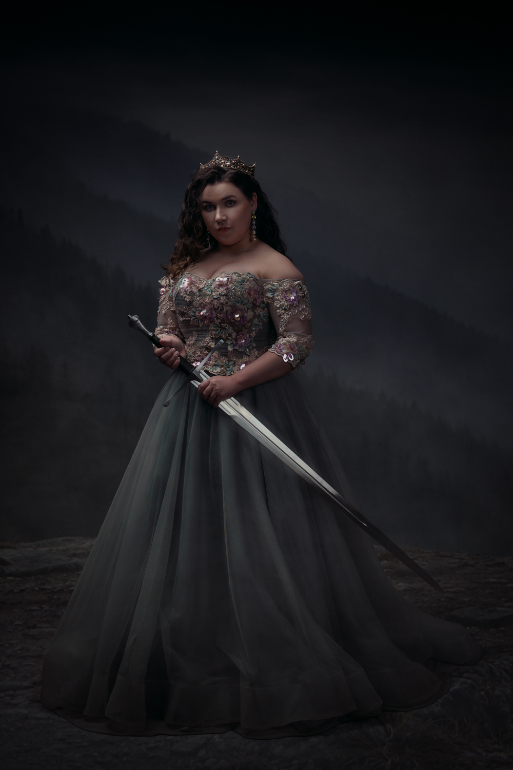 Ace Photography fine art meesterwerk fotoshoot van dame in mooie groene jurk met rose glitterstenen en en zwaard in de hand. Ze staat op een klif van een berg en kijkt in de camera met een neutrale blik