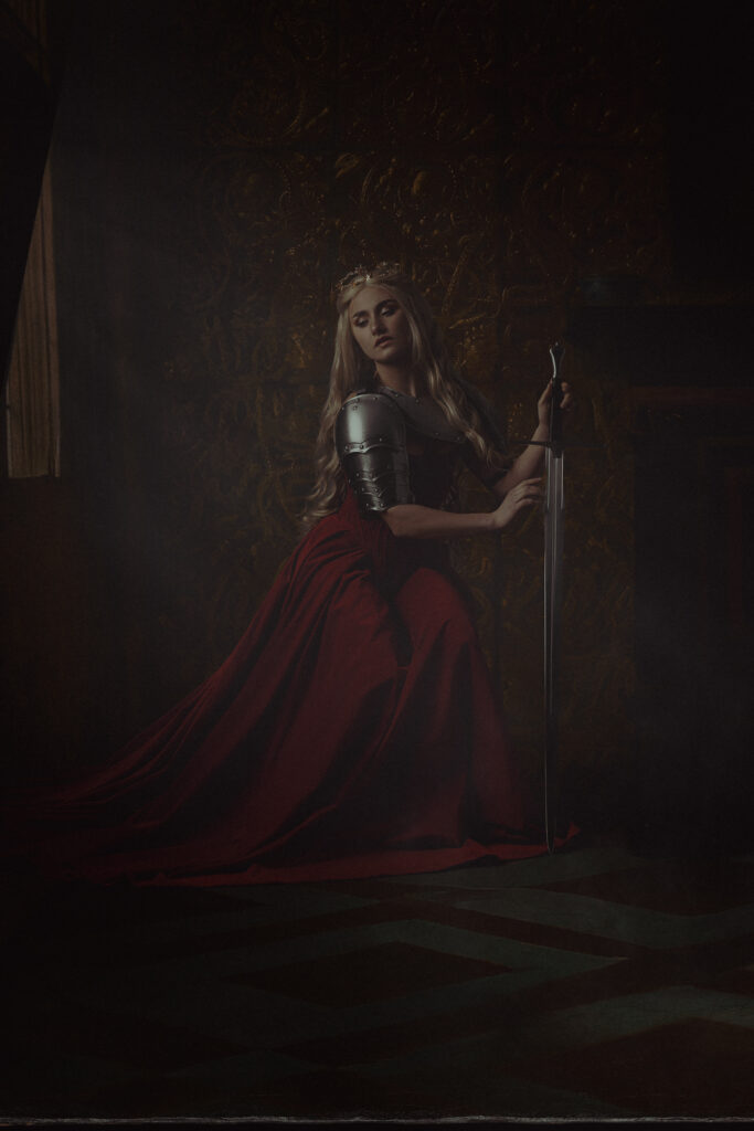 Theatraal fine art portret vrouw rode jurk met kroon bij raam in gouden kamer — Meesterwerk Ace Photography Zaltbommel